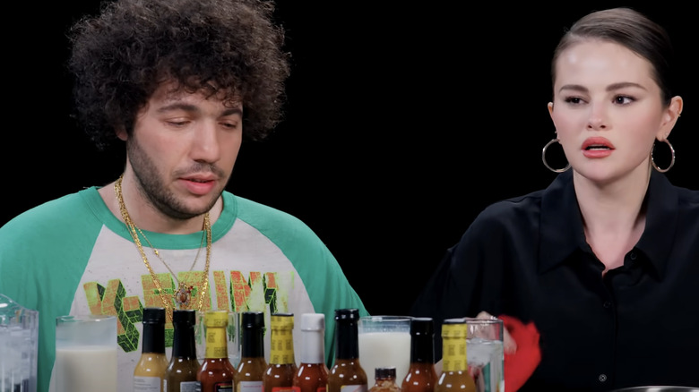 Benny Blanco and Selena Gomez glaring at the Hot Ones hot sauce in pain