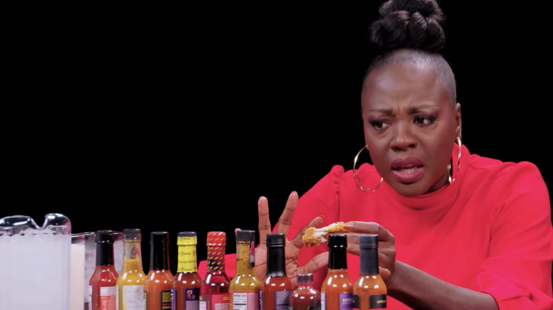 Viola Davis looking upset in front of hot sauce lineup on Hot Ones