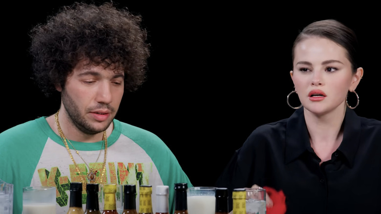 Benny Blanco and Selena Gomez glaring at the Hot Ones hot sauce in pain