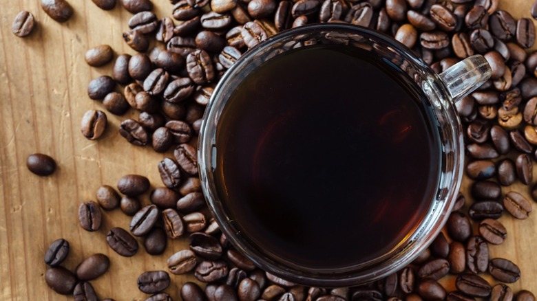 Cup of brewed coffee on bean background