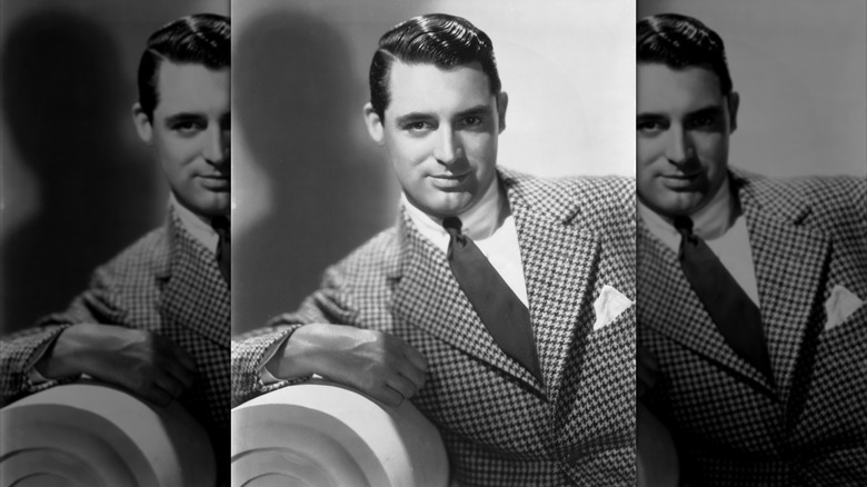 Actor Cary Grant leaning on a chair arm.
