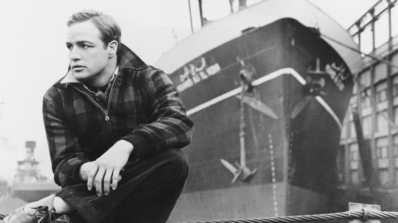 Actor Marlon Brando posing in front of a large ship.