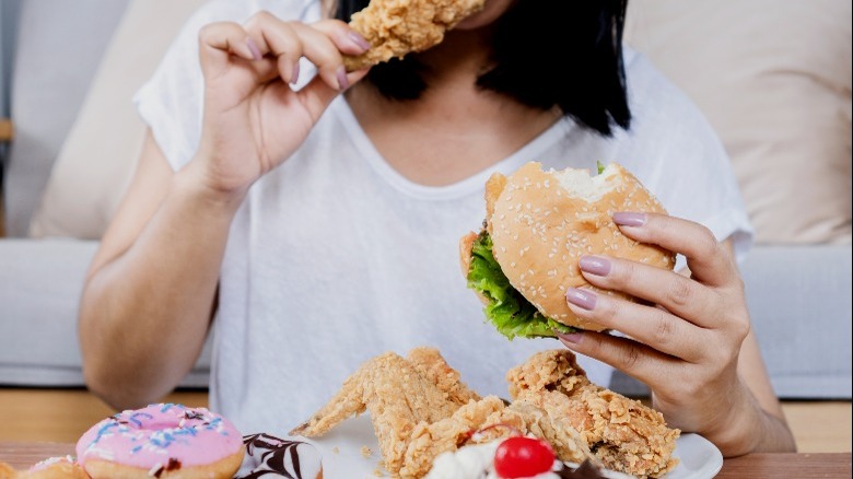Woman eating donut, burger, chicken