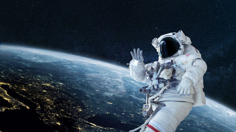 Astronaut waving in space with earth behind them