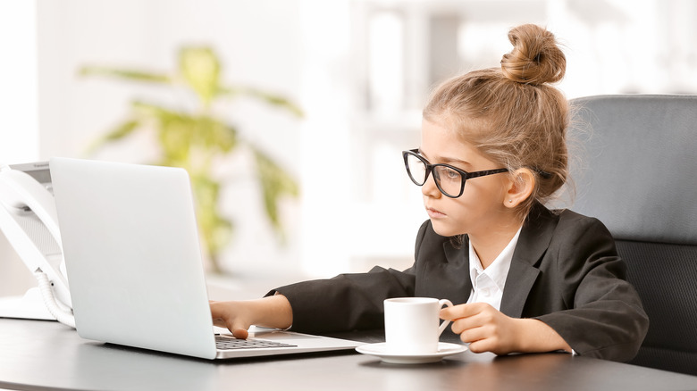 Kid wearing glasses at laptop with hot mug