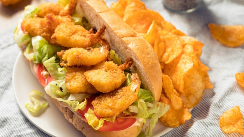 A shrimp po' boy sandwich with chips