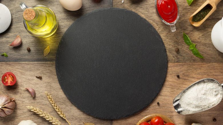 A round pizza stone around pizza ingredients 