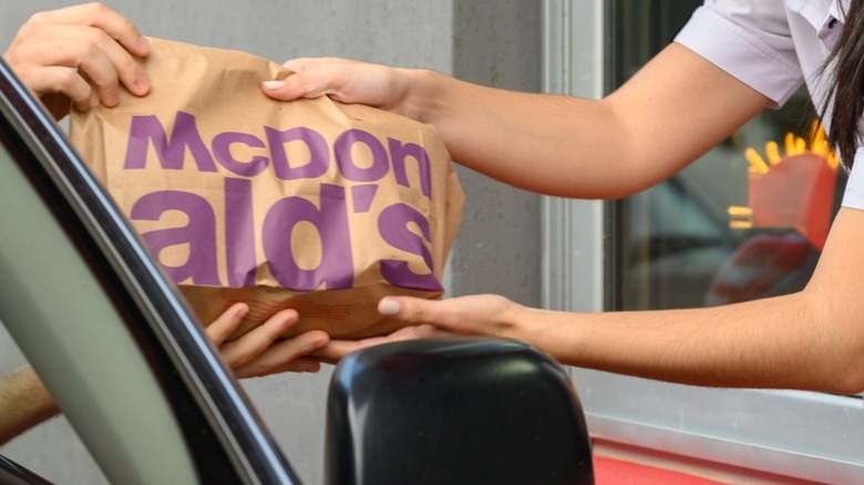 McDonald's employee handing bag out drive-thru window