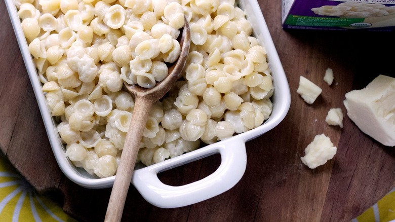 Annie's mac and cheese shell pasta in a baking dish with wooden spoon