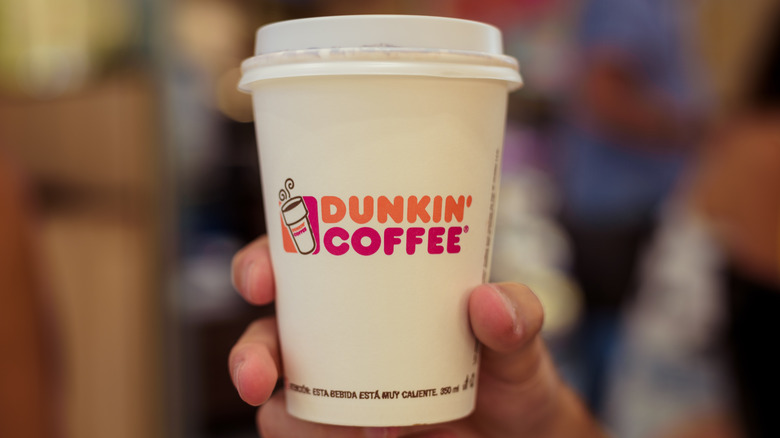 person holding Dunkin' coffee cup