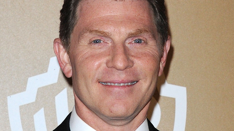 Bobby Flay standing against tan wall