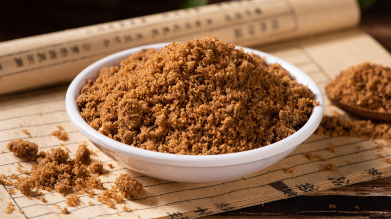 A bowl of dark brown sugar with a smaller bowl filled nearby