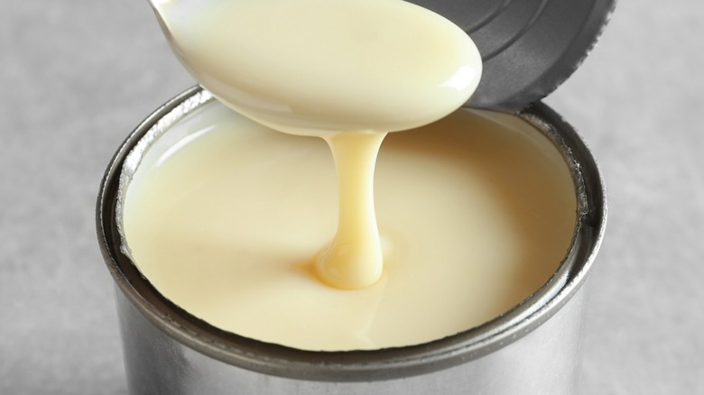 spoon scooping evaporated milk out of a can