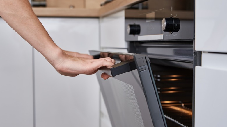 Two hands opening oven door