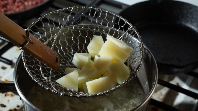 Spider strainer pulling up potatoes from pot