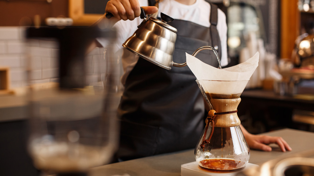 Person pouring water over a coffee