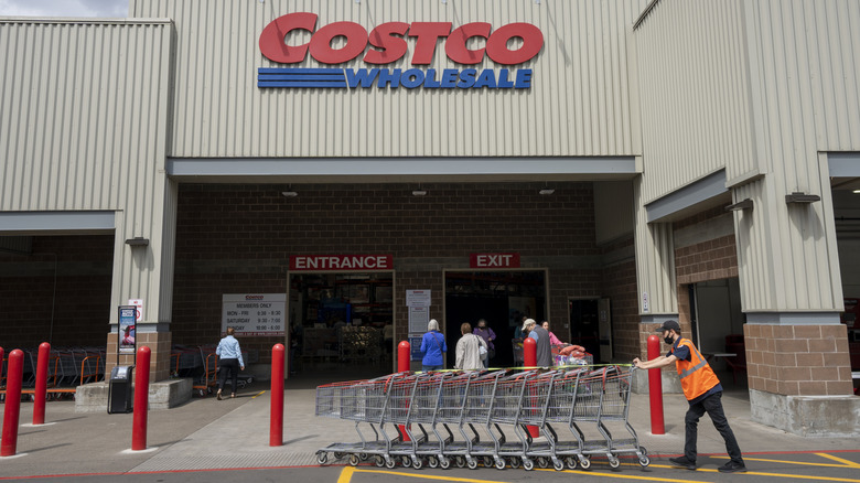 Employee pushes a line of shopping carts in front of a Costco