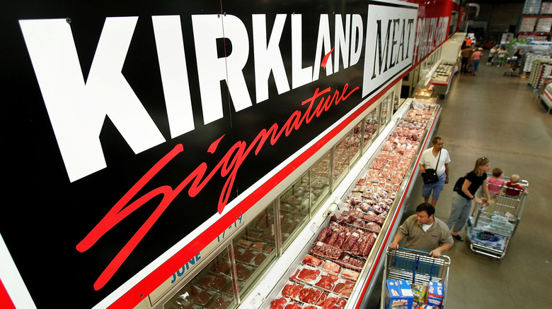Kirkland Signature sign above shoppers in the meat aisle at Costco.