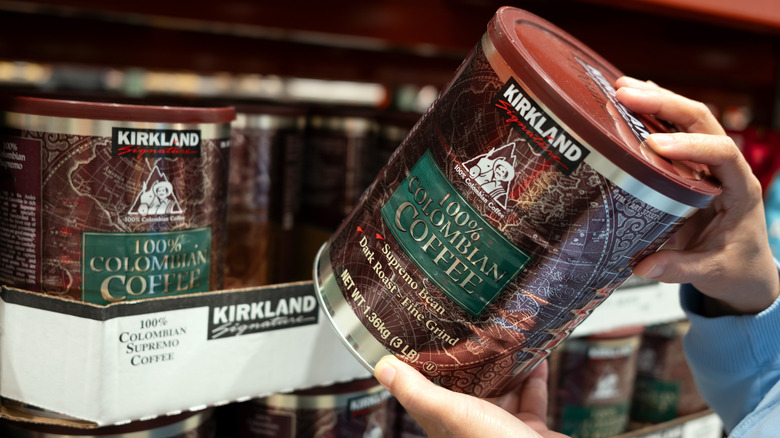Customer pulls a large can of Kirkland Signature Colombian coffee from a shelf at Costco