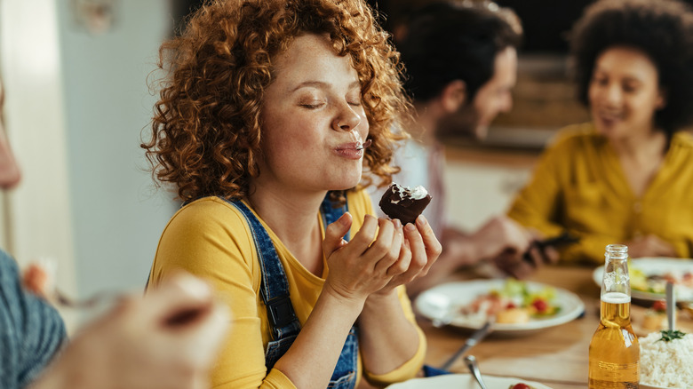 Woman with eyes closed enjoying piece of food
