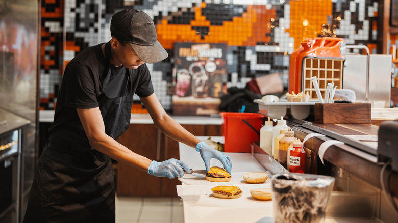Employee preparing fast food burger inside a restaurant kitchen