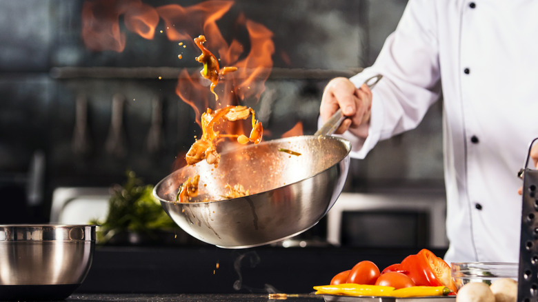 Chef tossing ingredients in flaming pan