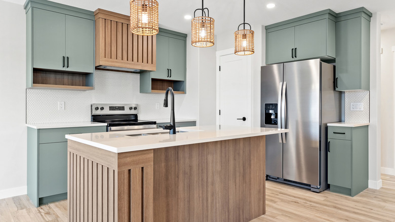 A modern-looking kitchen with green cabinets and lights