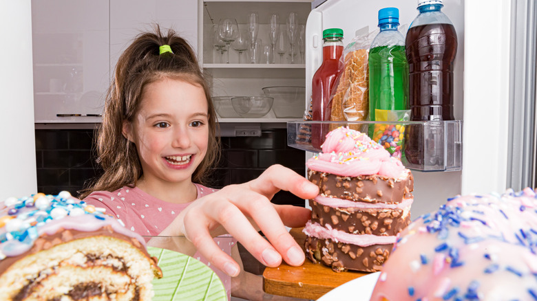Girl getting cake from refrigerator