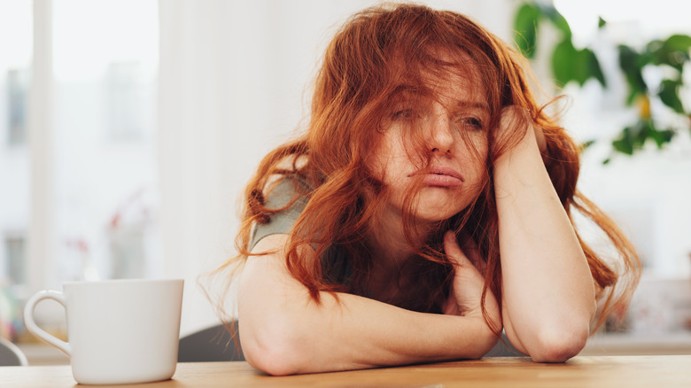 Woman with messy red hair and elbows on the table