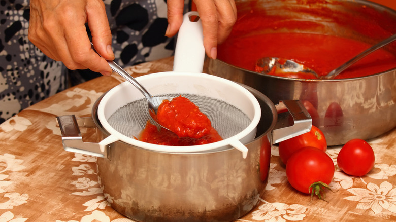 Person straining tomato mixture