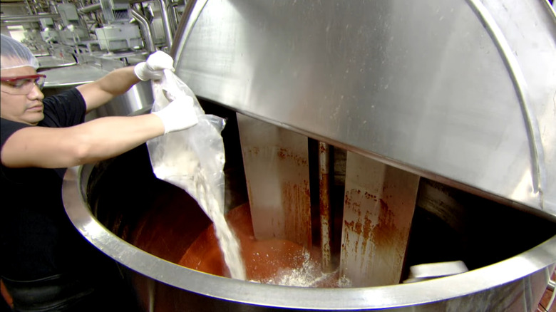 Worker adding spices during ketchup production