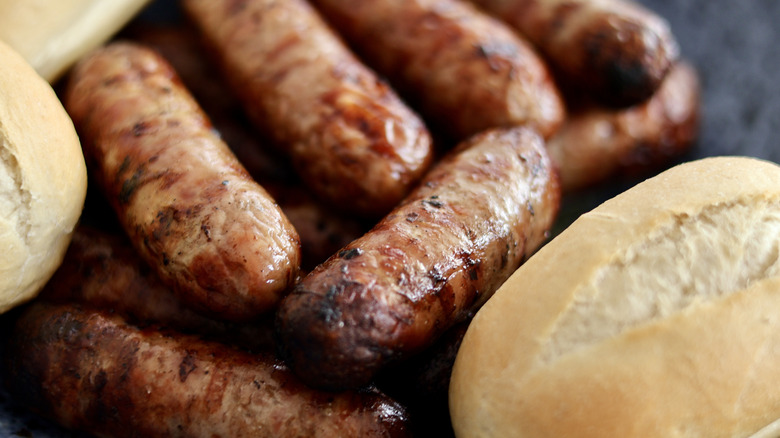 A plate of cooked German bratwurst with two pieces of bread