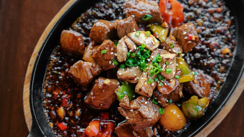 Stir-fried steak and vegetables served on a sizzling plate.
