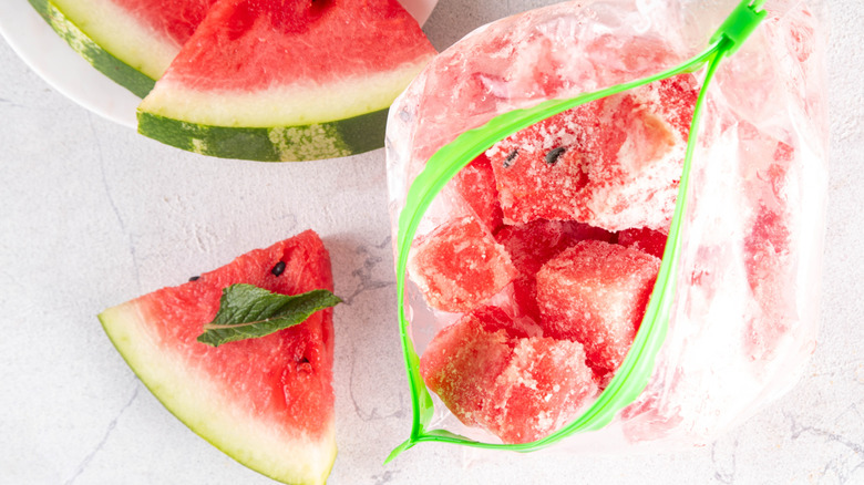 Cubes of frozen watermelon in open zip-top bag with watermelon wedges