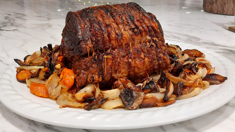 A tied and roasted whole prime rib served on a white platter.