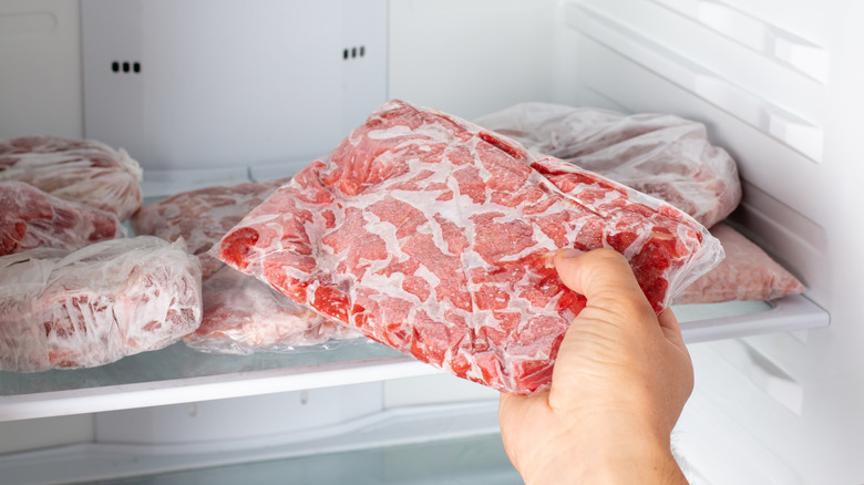 Hand removing frozen ground beef from freezer