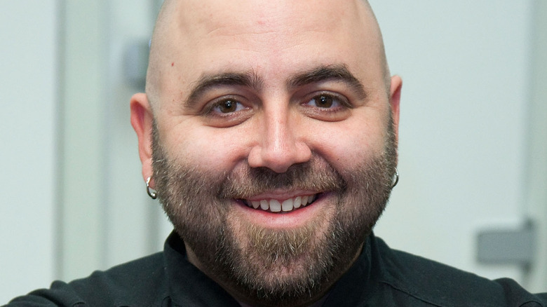 Duff Goldman smiles with earrings and a beard