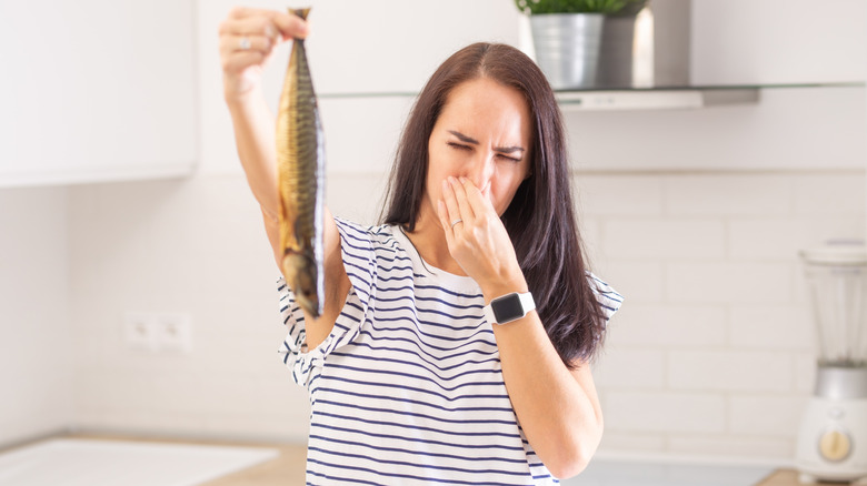 Person holding up spoiled fish and holding their nose