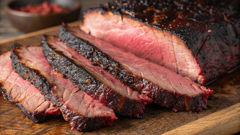 Smoked brisket with dark crust on wooden cutting board