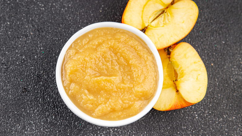 Apple sauce in a bowl beside halved apple