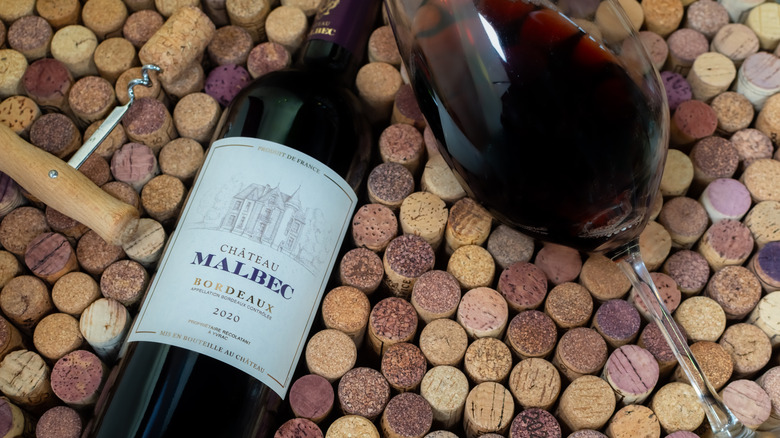 Malbec bottle with wine glass and opener on corks