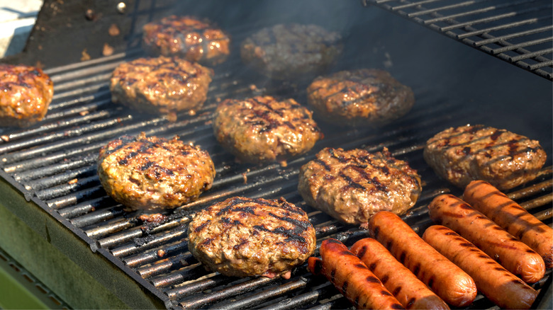 Burgers and hot dogs cooking on grill.
