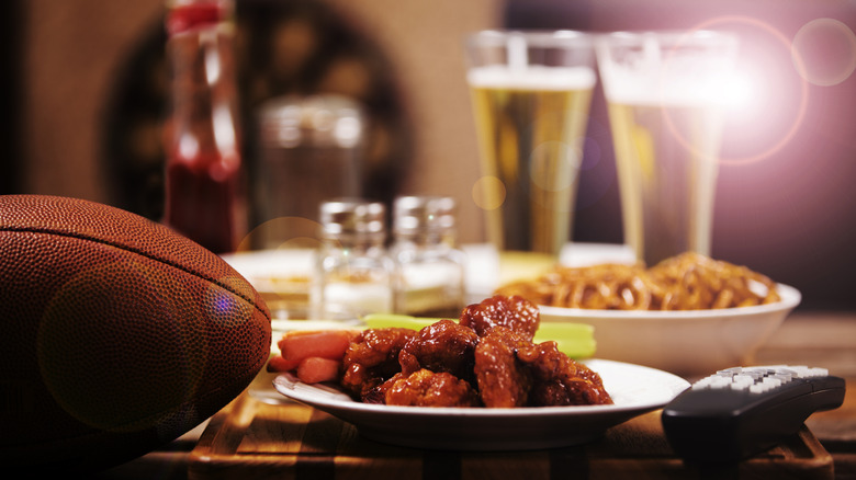 Chicken wings, football, and beer on table