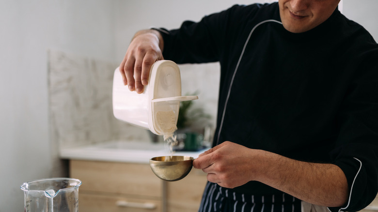 Person pouring flour into measuring cup