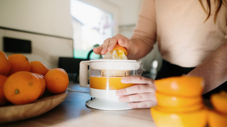 Person juicing oranges in kitchen.