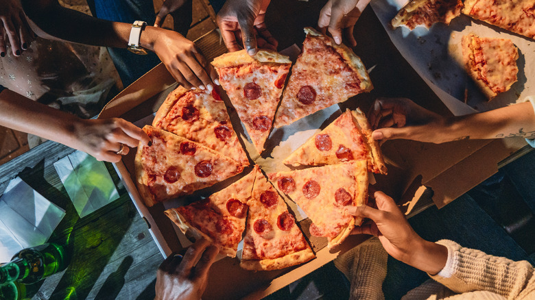 Hands grabbing pizza at party