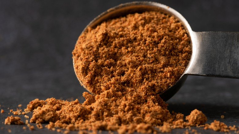 A measuring spoon pours out taco seasoning.