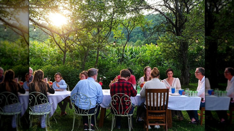 Christopher Kimball and Melissa Baldino sitting at a large outdoor table with family and friends