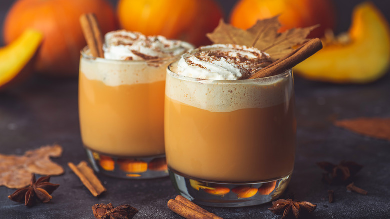 two pumpkin spice lattes in front of pumpkins
