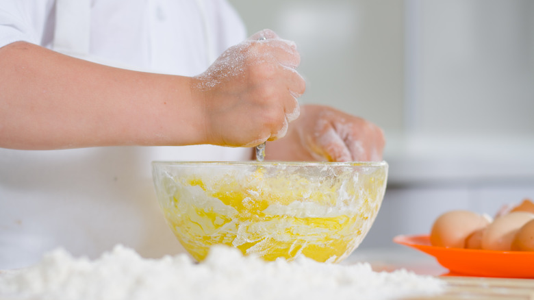 A kid mixing flour and eggs in a bowl